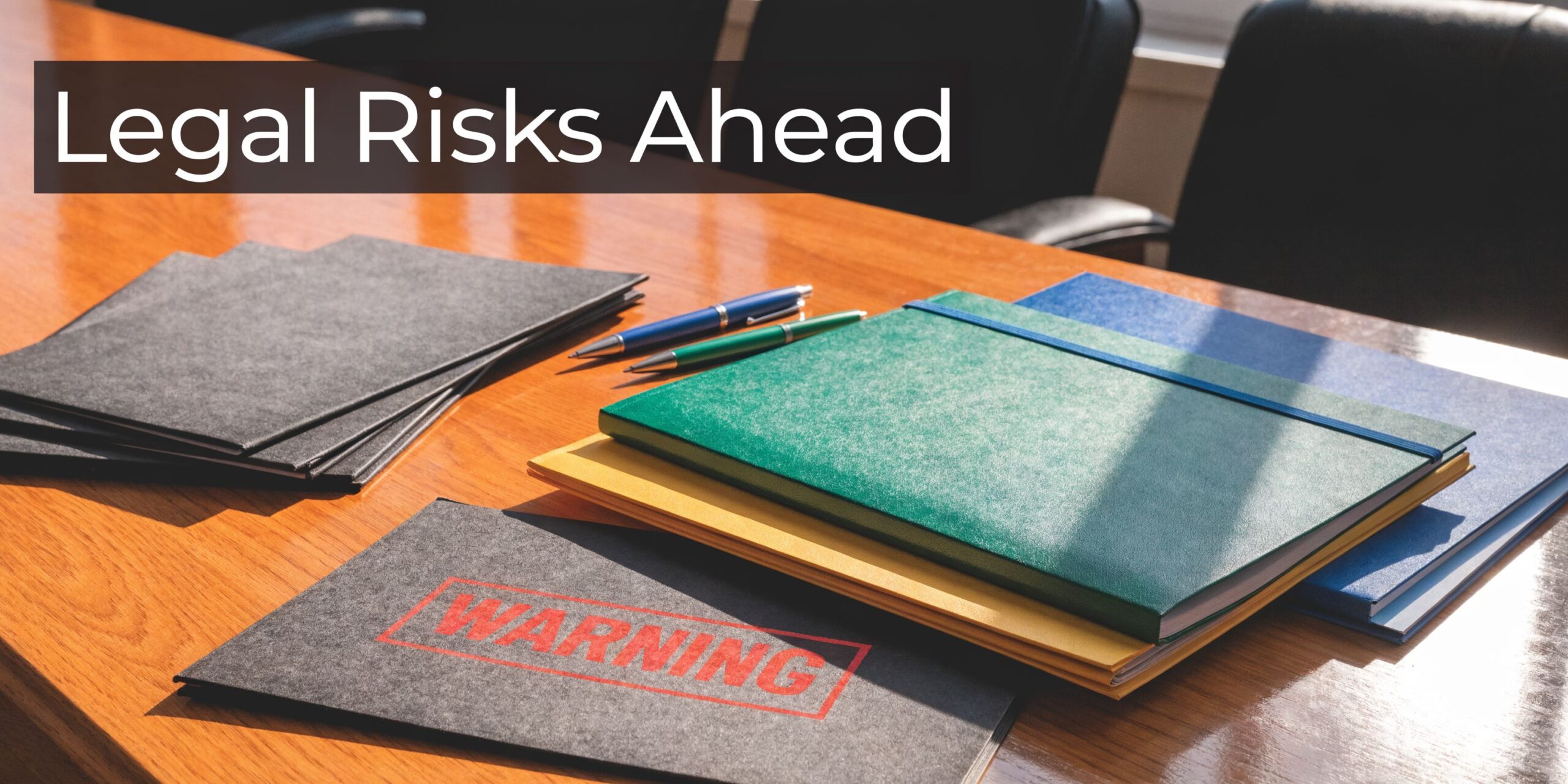 A wooden conference table with stacks of folders, pens, and a document with a bold warning label.