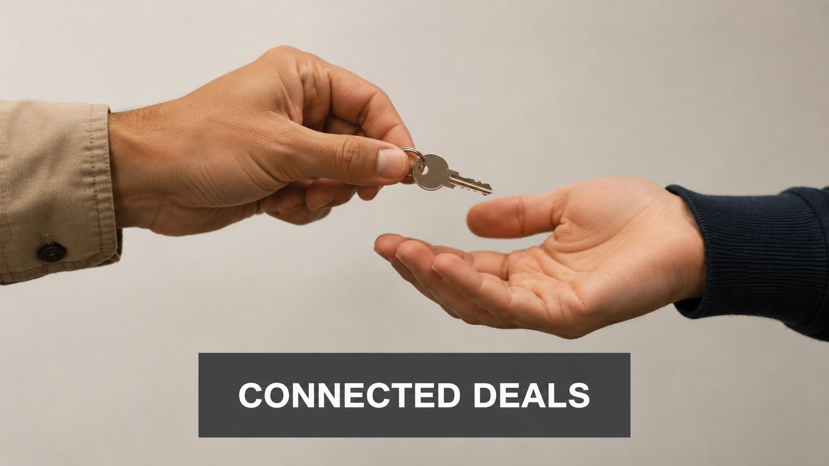 A person handing a metal house key to another person against a plain light background
